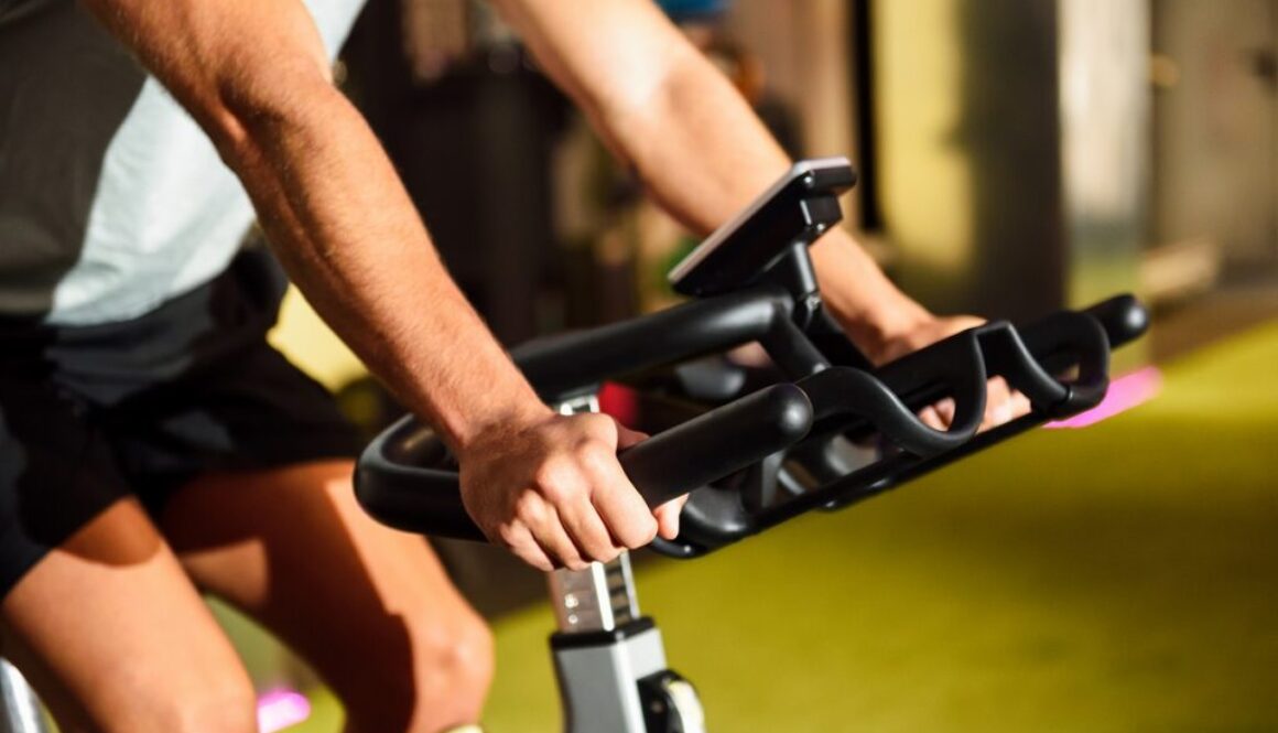 Hands of a man training at a gym doing cyclo indoor.