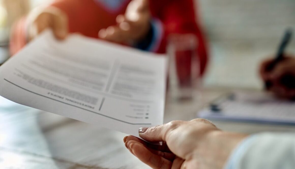 Close-up of a candidate giving his CV while applying for a job.