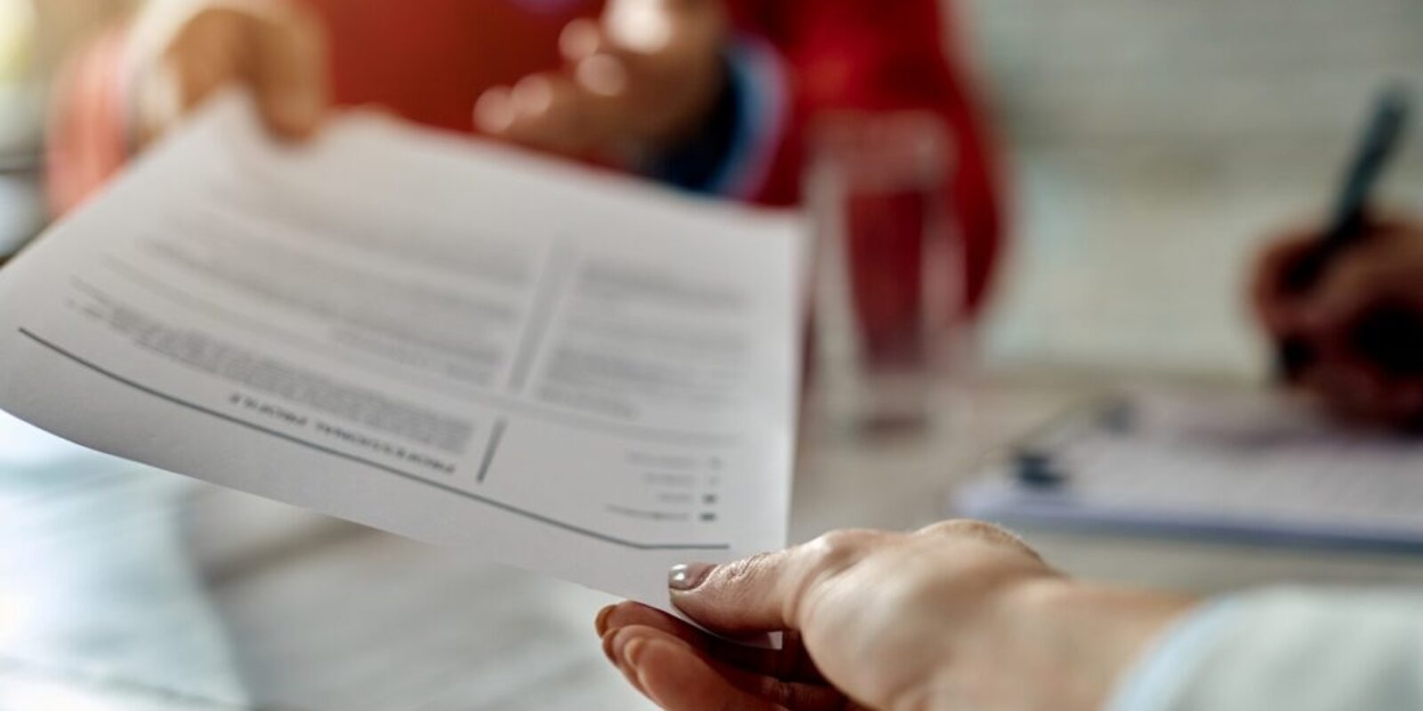 Close-up of a candidate giving his CV while applying for a job.